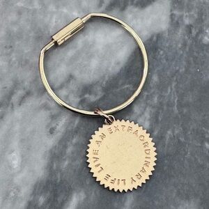 India Hicks gold key chain with charm that says Live An Extraordinary Life